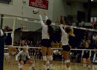 Freshman Ashley Keck and senior Camryn Opfer block a shot from College St. Mary (Image credit: Lexi Swenson)